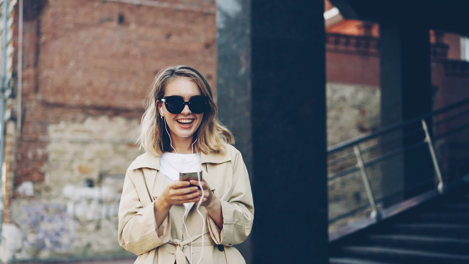 Una mujer sonríe mientras usa su celular en la calle